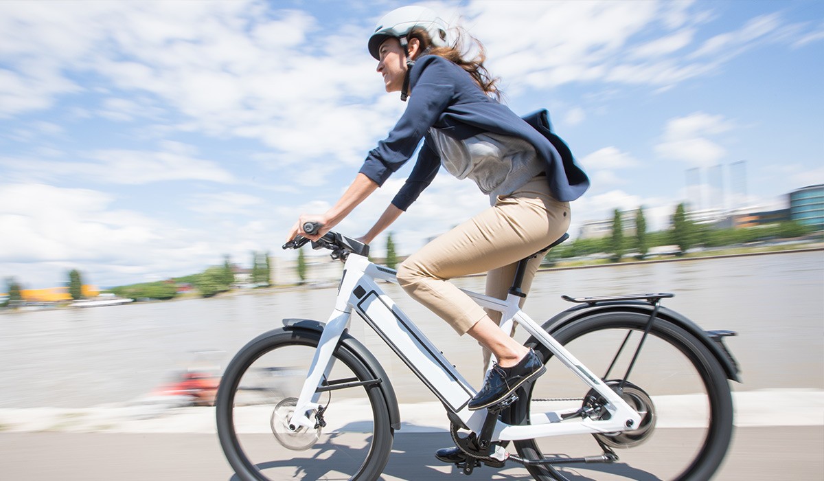 Get started with the Stromer leasing offers for employees: Woman riding her ST3 along the river.   