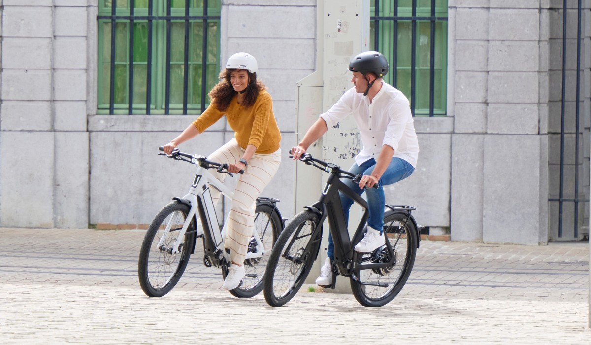 Woman and man ride in the city on their fast Stromer ST3 e-bikes up to 45 km/h.