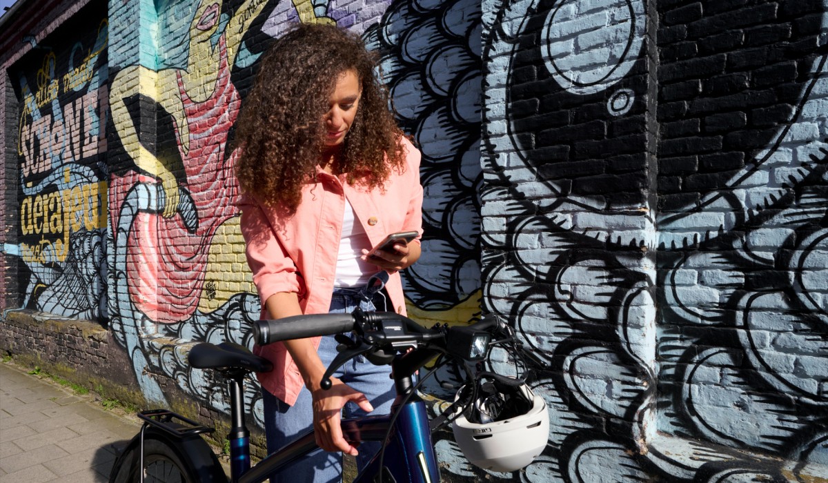 Une femme avec le Stromer ST1 Special Edition – parfaitement reliée au vélo avec l'appli OMNI.