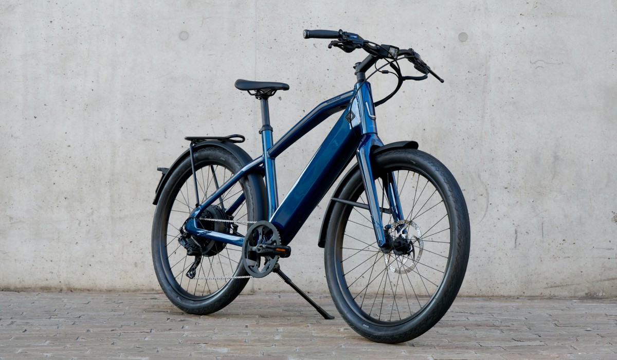 De Stromer ST1 Special Edition – de e-bike tot 45 km/u in Deep Petrol voor een betonnen muur. 