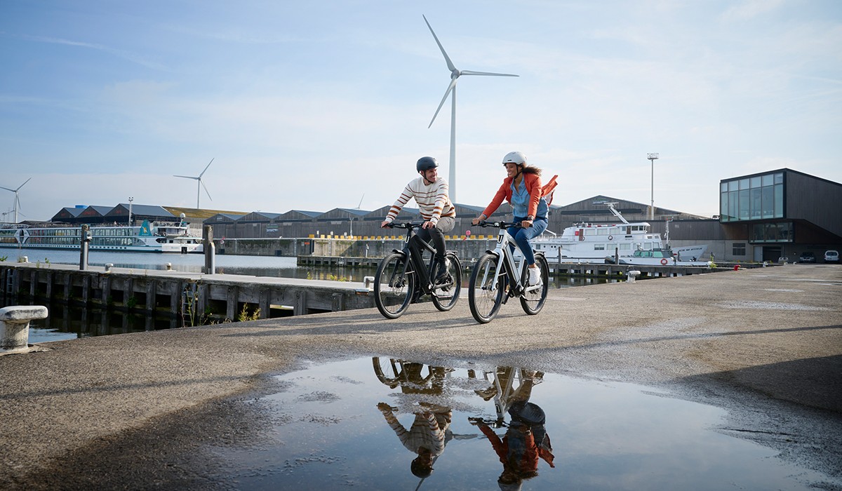 Dank E-Bike-Versicherung sicher unterwegs mit Stromer Speed Pedelecs: Mann und Frau fahren am Hafen entlang. 